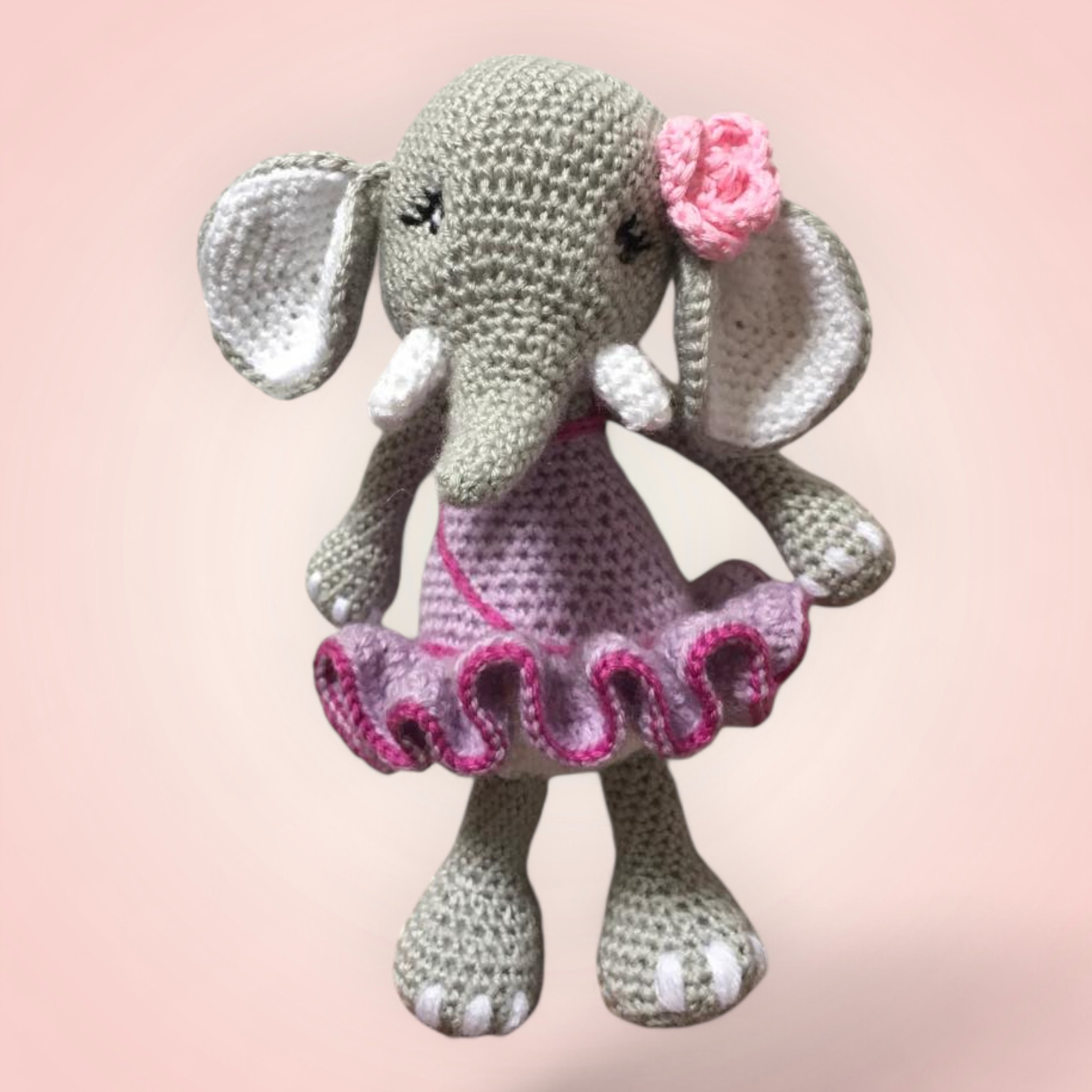 Adorable éléphant en crochet avec une jupe violette et une fleur rose.