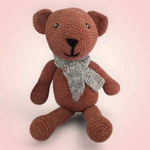 Adorable ours en crochet avec une écharpe grise.