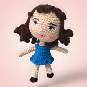 Charmante poupée brune au crochet avec une jupe bleue.