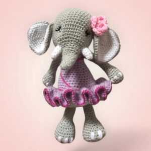 Adorable éléphant en crochet avec une jupe violette et une fleur rose.