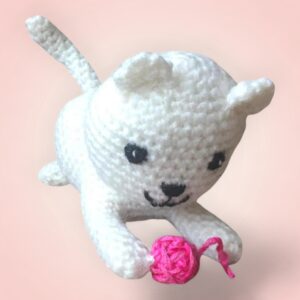 Adorable chat blanc en crochet avec une balle rose.