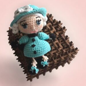 Élégante poupée en crochet représentant la Reine d'Angleterre, vêtue d'une robe turquoise.
