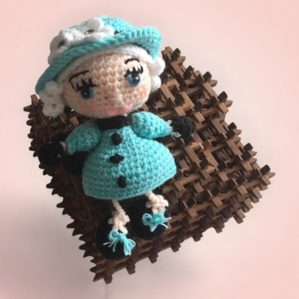 Élégante poupée en crochet représentant la Reine d'Angleterre, vêtue d'une robe turquoise.