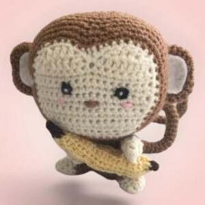 Adorable singe en peluche tenant une banane, fait main avec amour.